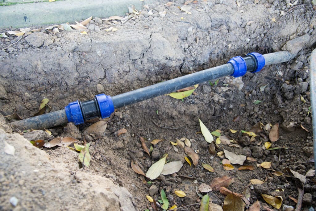 plastic, blue and black pvc pipe exposed in the yard outside a dallas home