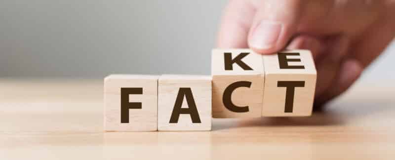 hand flipping word cube that says fake or fact