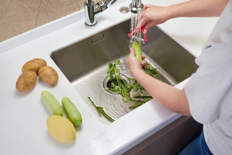woman peeling vegetables over the garbage disposal in her dallas kitchen sink