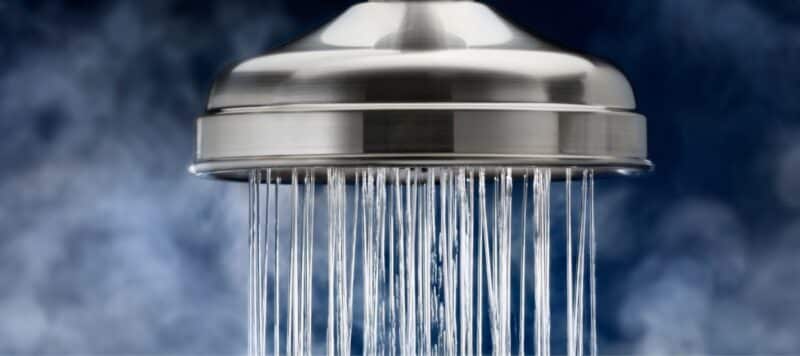 close up of water flowing from a large, circular silver shower head
