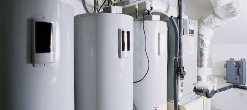 three white water heaters stacked in a line, ready to be installed