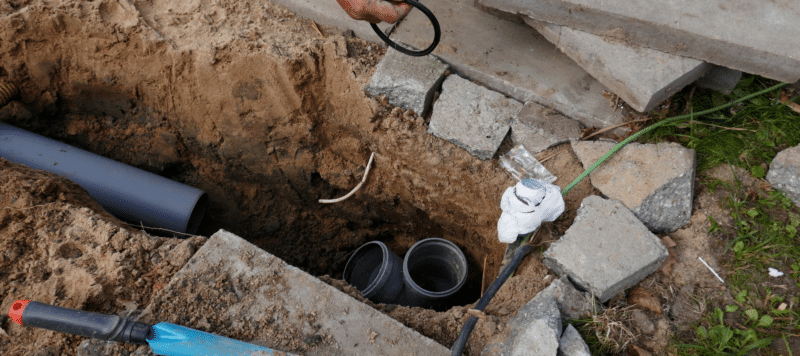 part of a yard that is dug up so new, dark gray pipe is visible