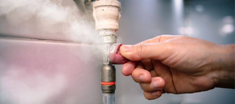 hand adjusting valve on vertical plumbing pipe that is releasing steam or gas