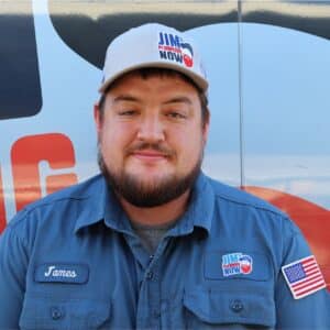Jim's Plumbing Now team member wearing branded cap and company uniform, smiling in front of a company van