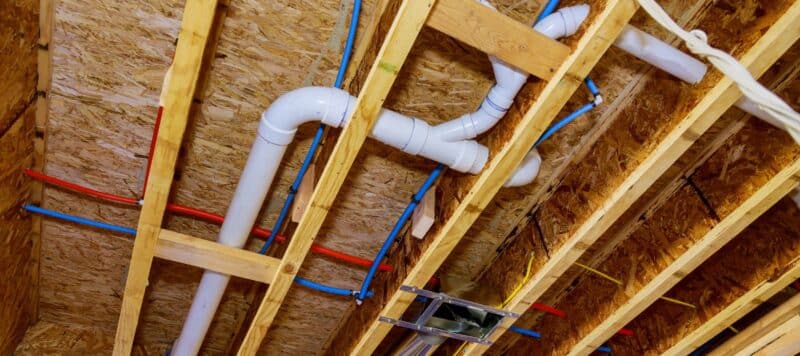 Home construction with hot and cold blue and red pex pipe layout in pipes and exposed beams